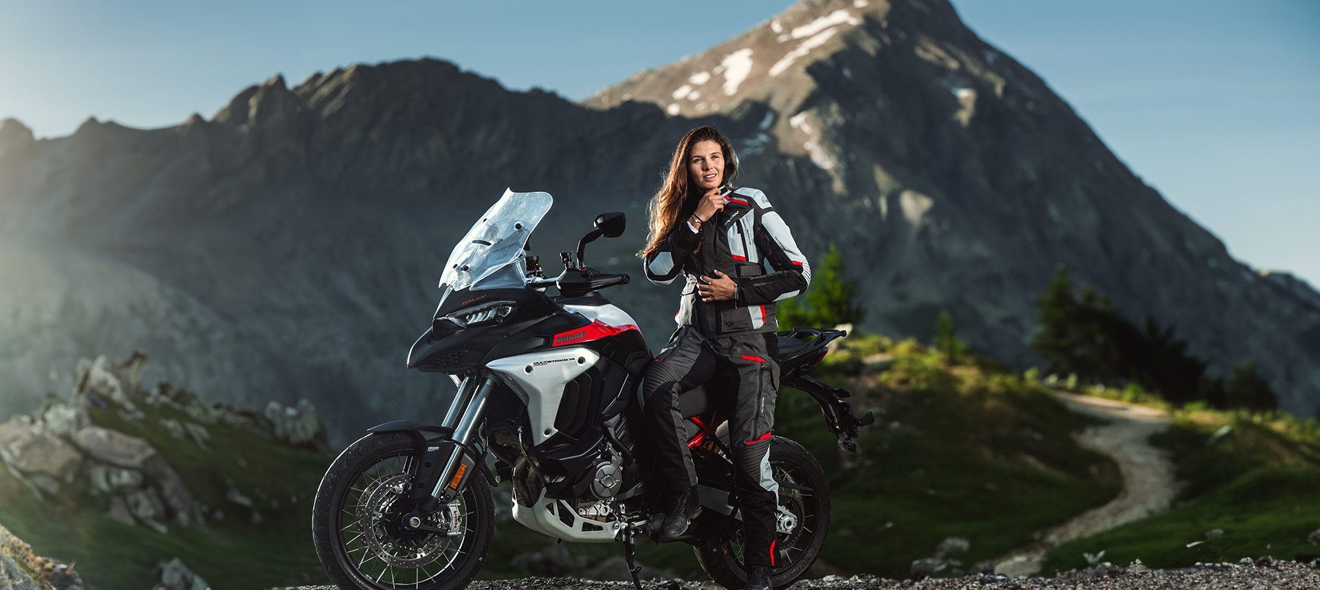 Chica en una moto con fondo montañoso